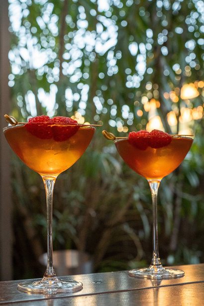 Two raspberry-topped coupes on a garden terrace bar