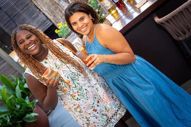 Two guests laughing with cocktails in hand