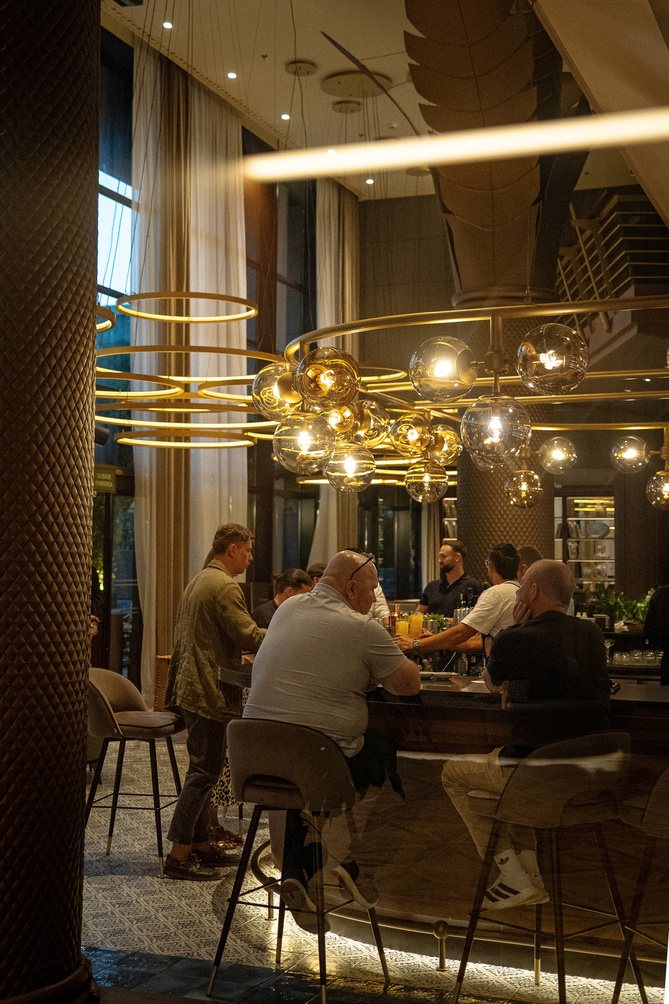 Hotel bar with gold chandelier and evening guests