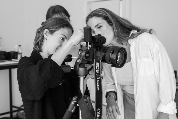 The founders framing a shot together behind a tripod