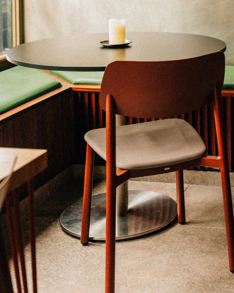A terracotta chair at a small café table with a single candle