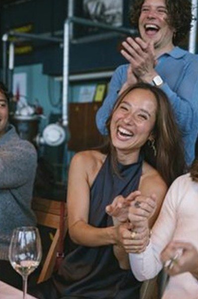 Guests clapping and laughing at a long table