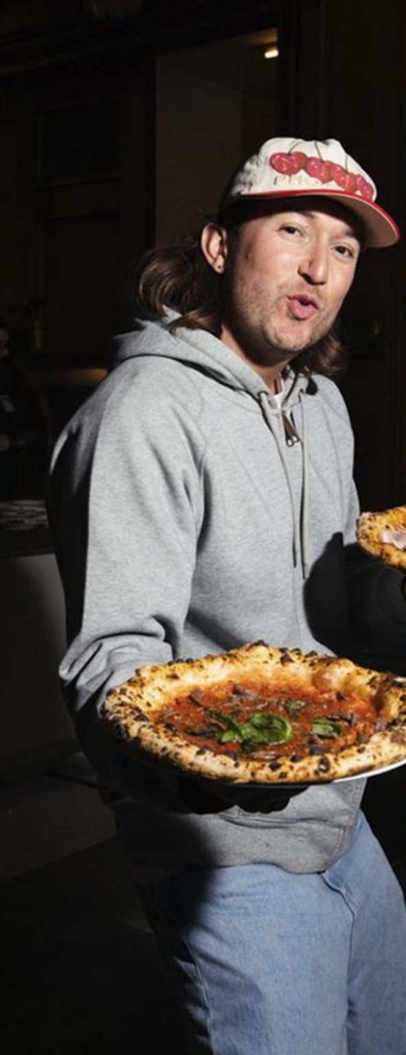 Guest holding a fresh Neapolitan pizza at a night event