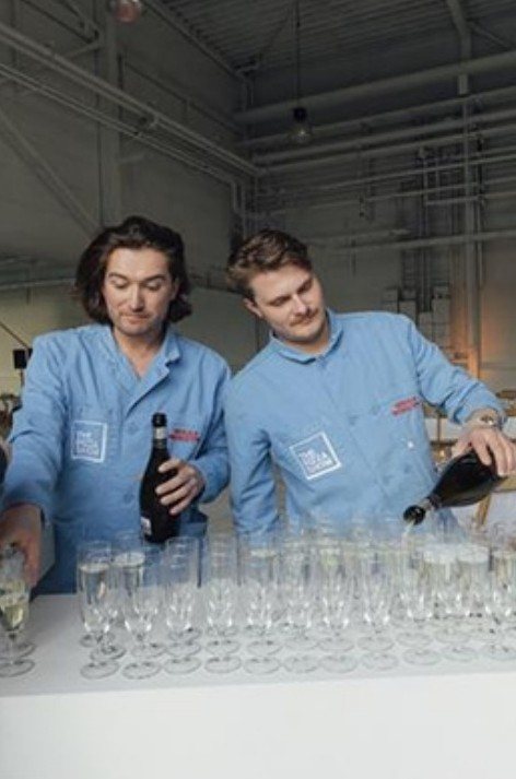Two hosts pouring sparkling wine into rows of flutes