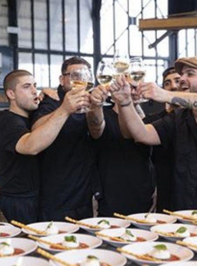 Kitchen team toasting over plated dishes