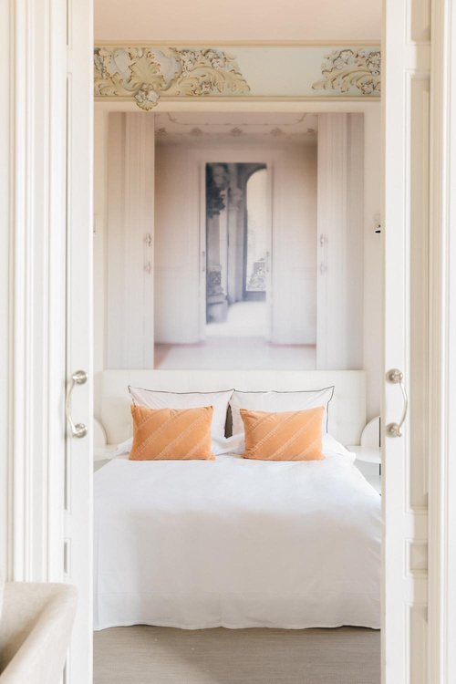 White bedroom with apricot cushions seen through double doors