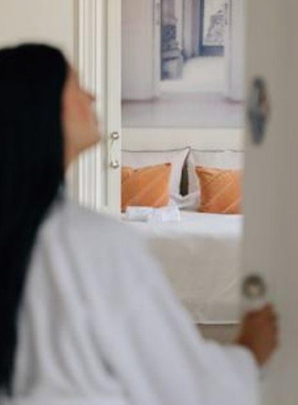 Guest in robe opening the door to a bright bedroom