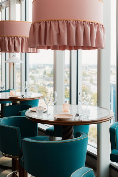 Rooftop dining room with pink lampshades and teal velvet chairs