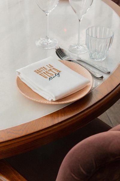 Embroidered Hasta la Vista napkin on a set table