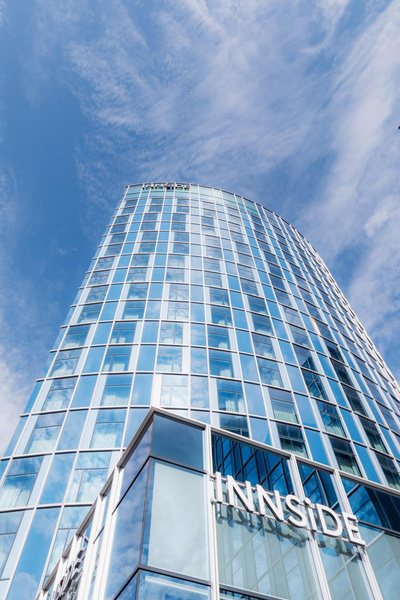Glass tower of INNSiDE by Meliá against a blue sky