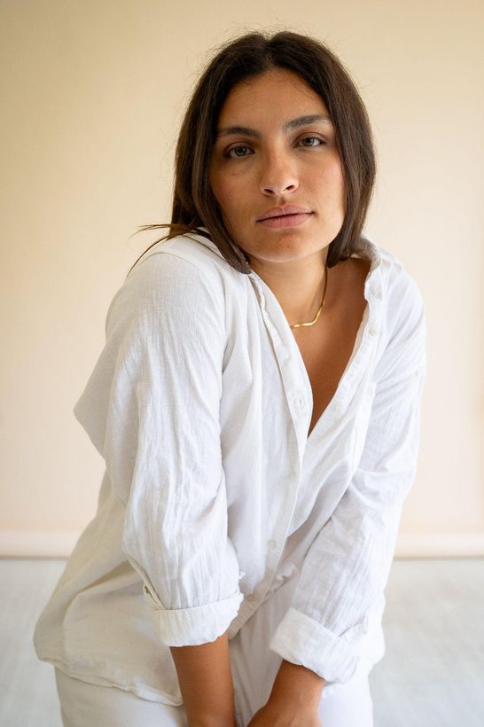 Studio portrait of a woman in white linen against a peach wall