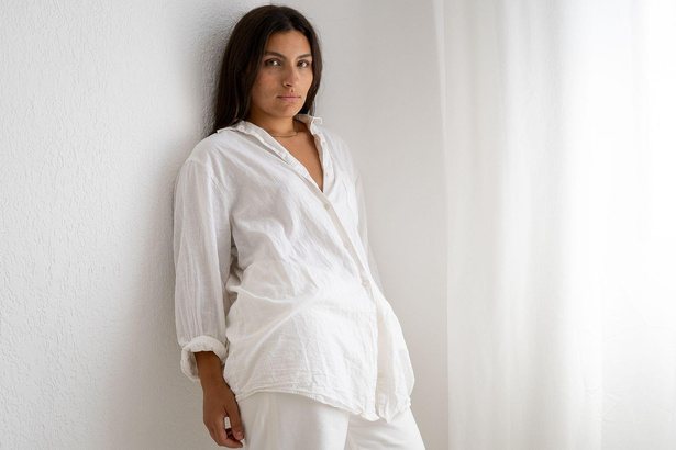 Portrait of a woman leaning against a white wall in soft light