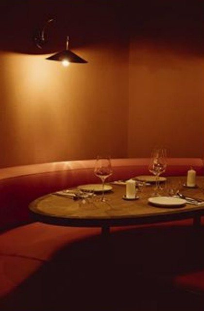 Candlelit red booth set for dinner