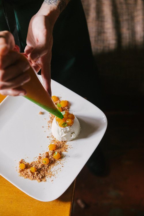 Chef piping sauce around a burrata dessert