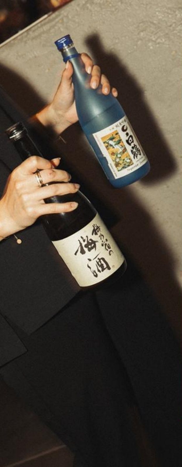 Hands presenting two bottles of Japanese sake and umeshu