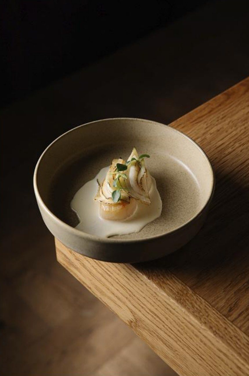 Scallop dish in a stoneware bowl on an oak counter