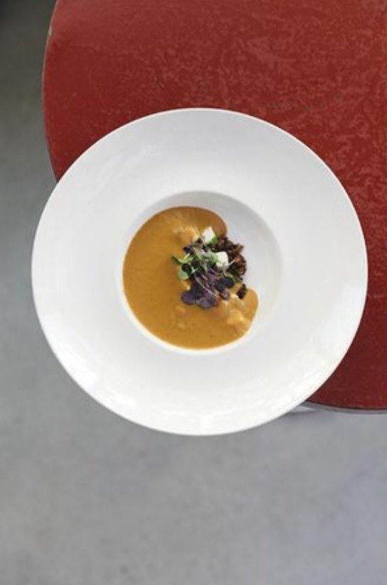 Bisque in a wide white bowl on a red charger
