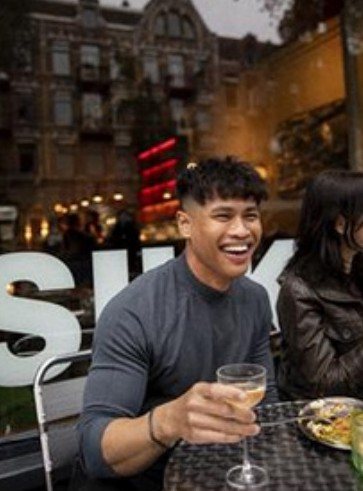 Guest smiling with a glass of wine outside the restaurant