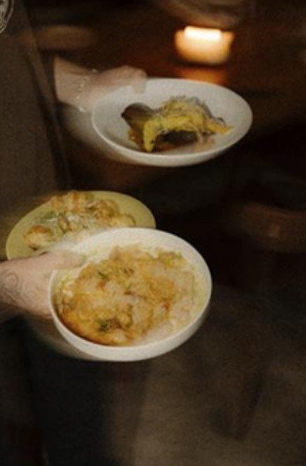 Server carrying plates through a candlelit room