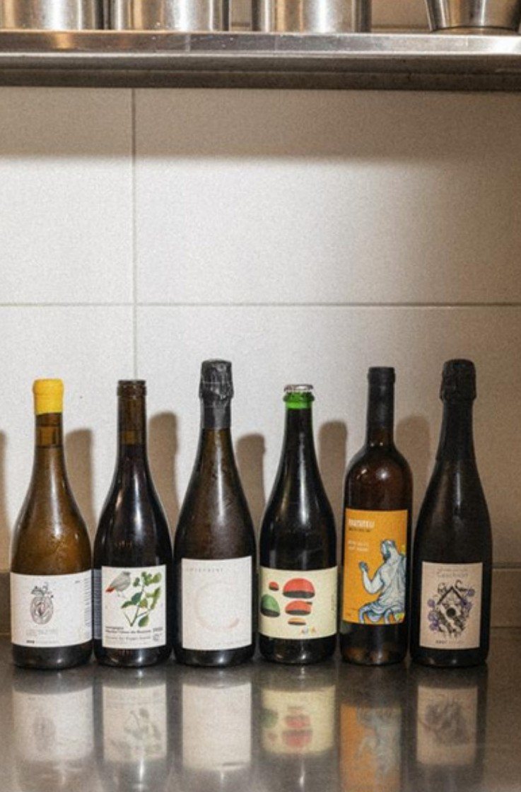 Row of natural wine bottles on a steel counter