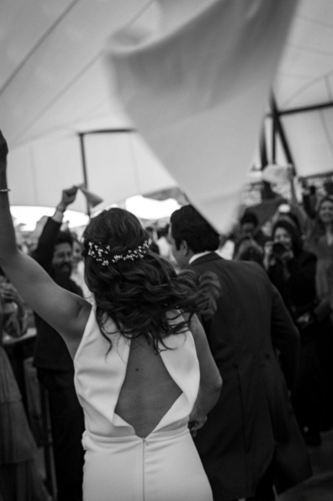 Bride with arms raised on a crowded dance floor