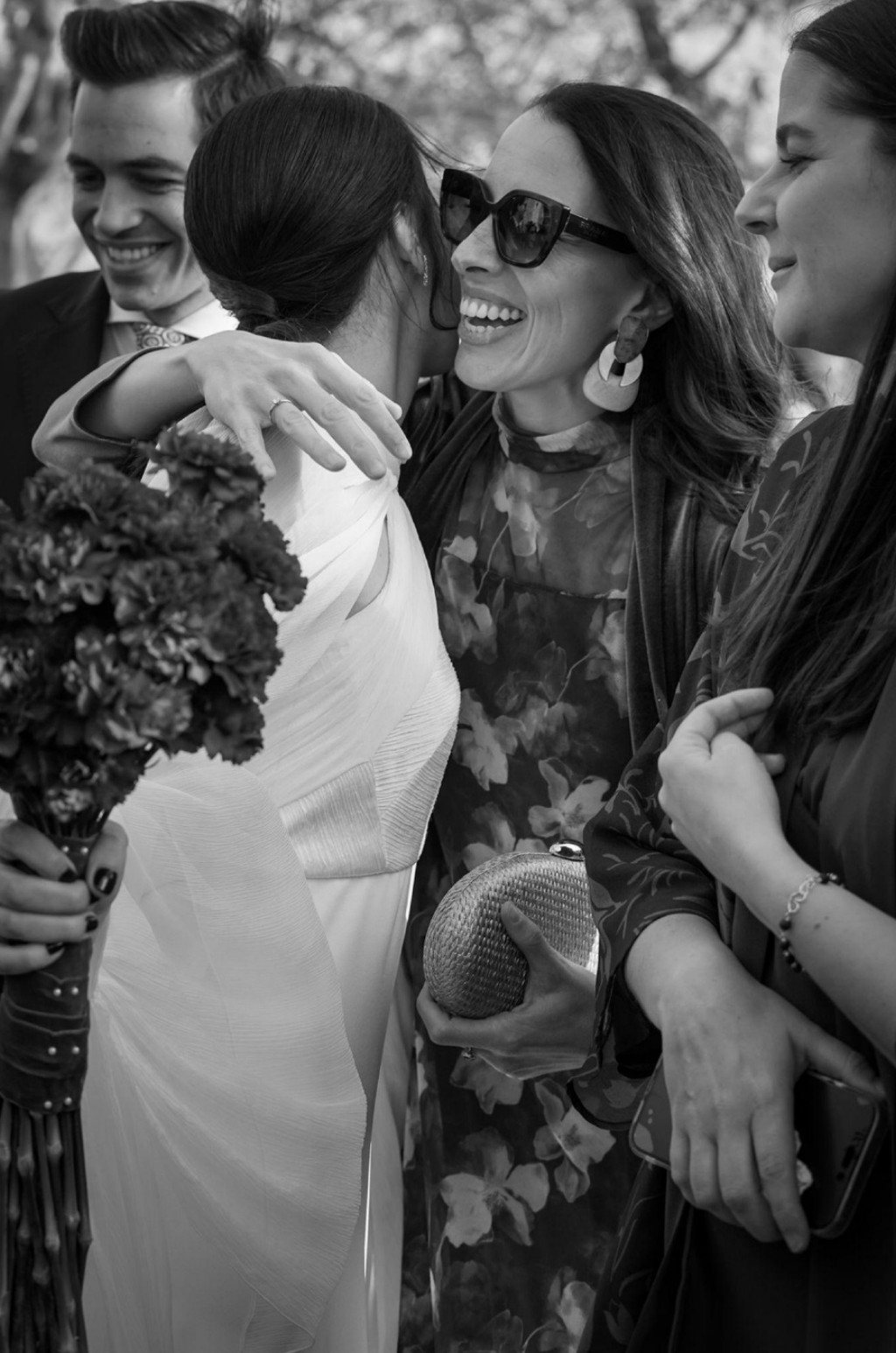 Black-and-white moment of a bride embraced by a guest