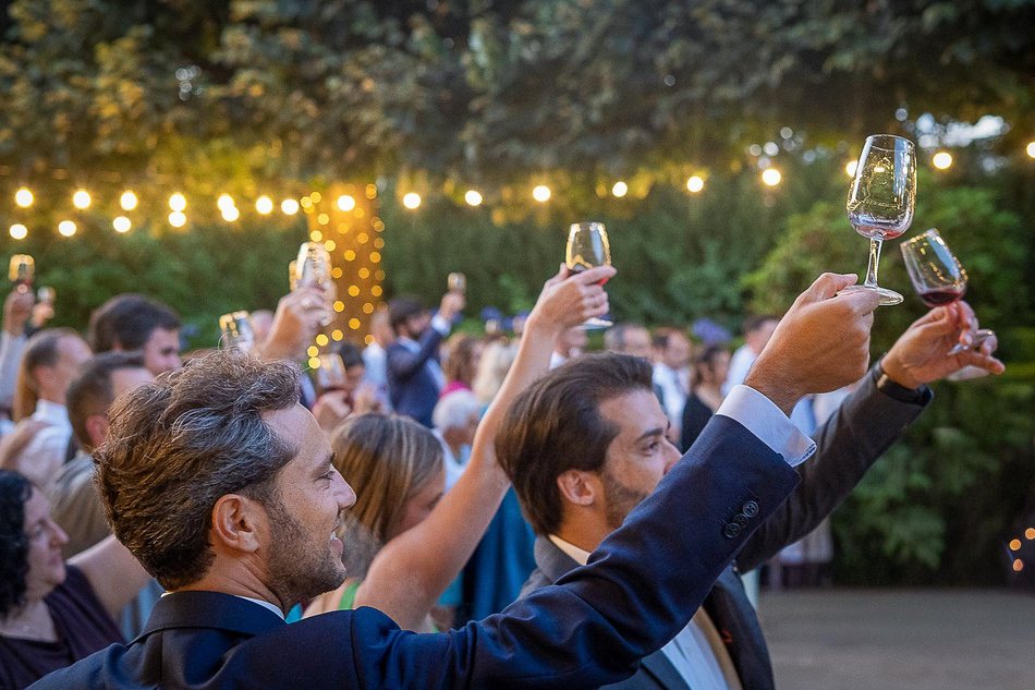 Wedding guests raising glasses under string lights